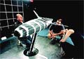 Three PACT95 engineers inspecting an early hull design of Young America ina Wind Tunnel.
